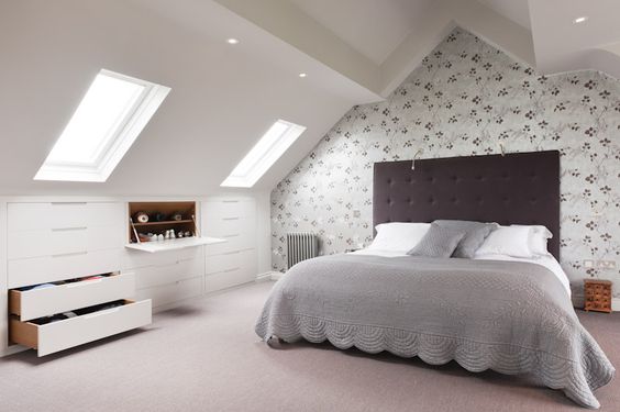 An image of a light and contemporary bedroom in a loft conversion with skylight windows