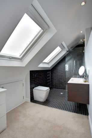 A photo showing a loft conversion space used as a modern bathroom with two skylight windows