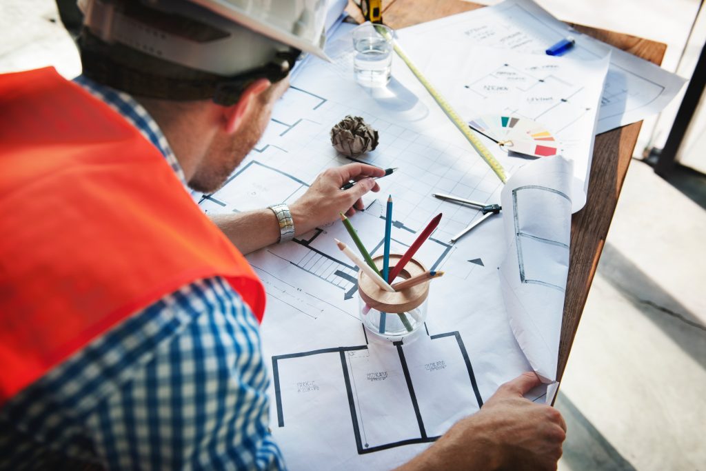 An image showing a builder or architect leaning over blueprints for a building conversion