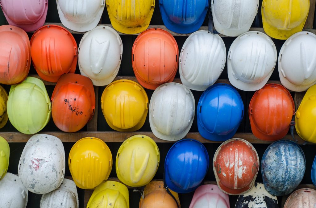 An image showing multicoloured builders hats lined up on a wall