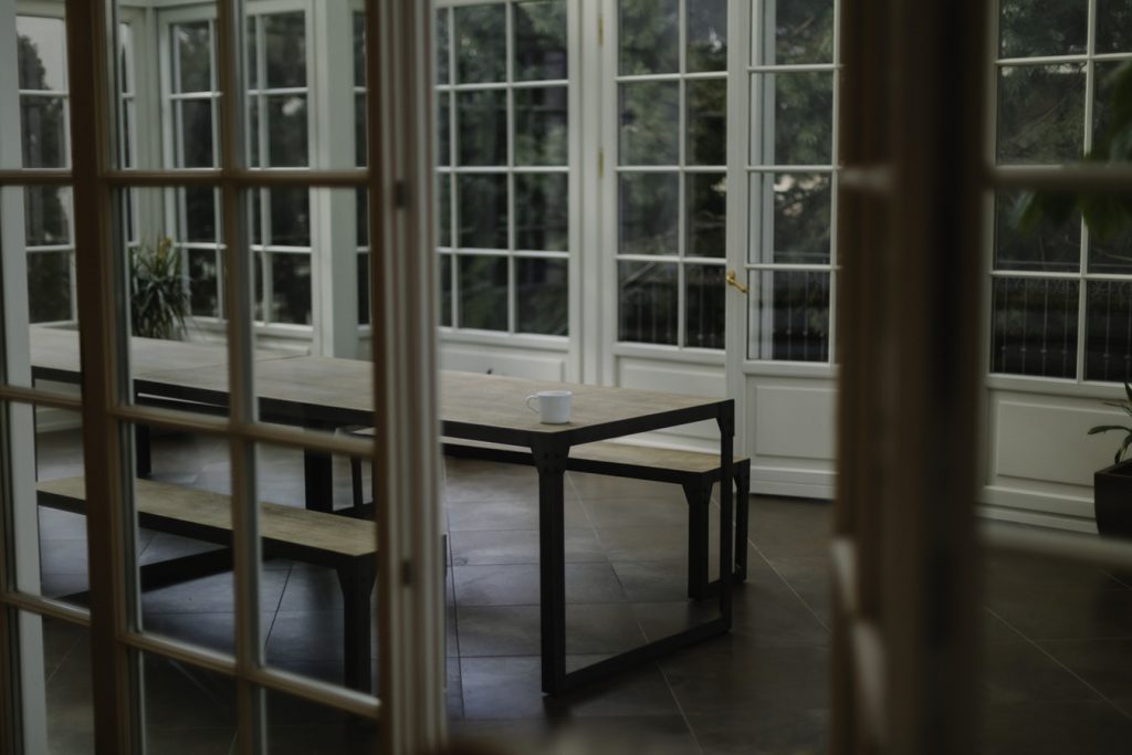 A photo showing a large conservatory with glass doors and paved flooring