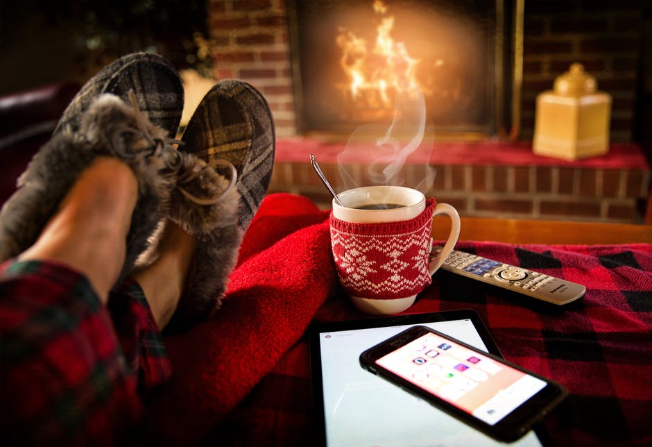 An image showing a roaring fire, hot drink and fluffy slippers